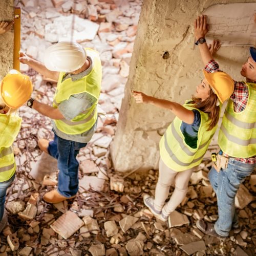 Four construction architects review plan in building damaged in the disaster.